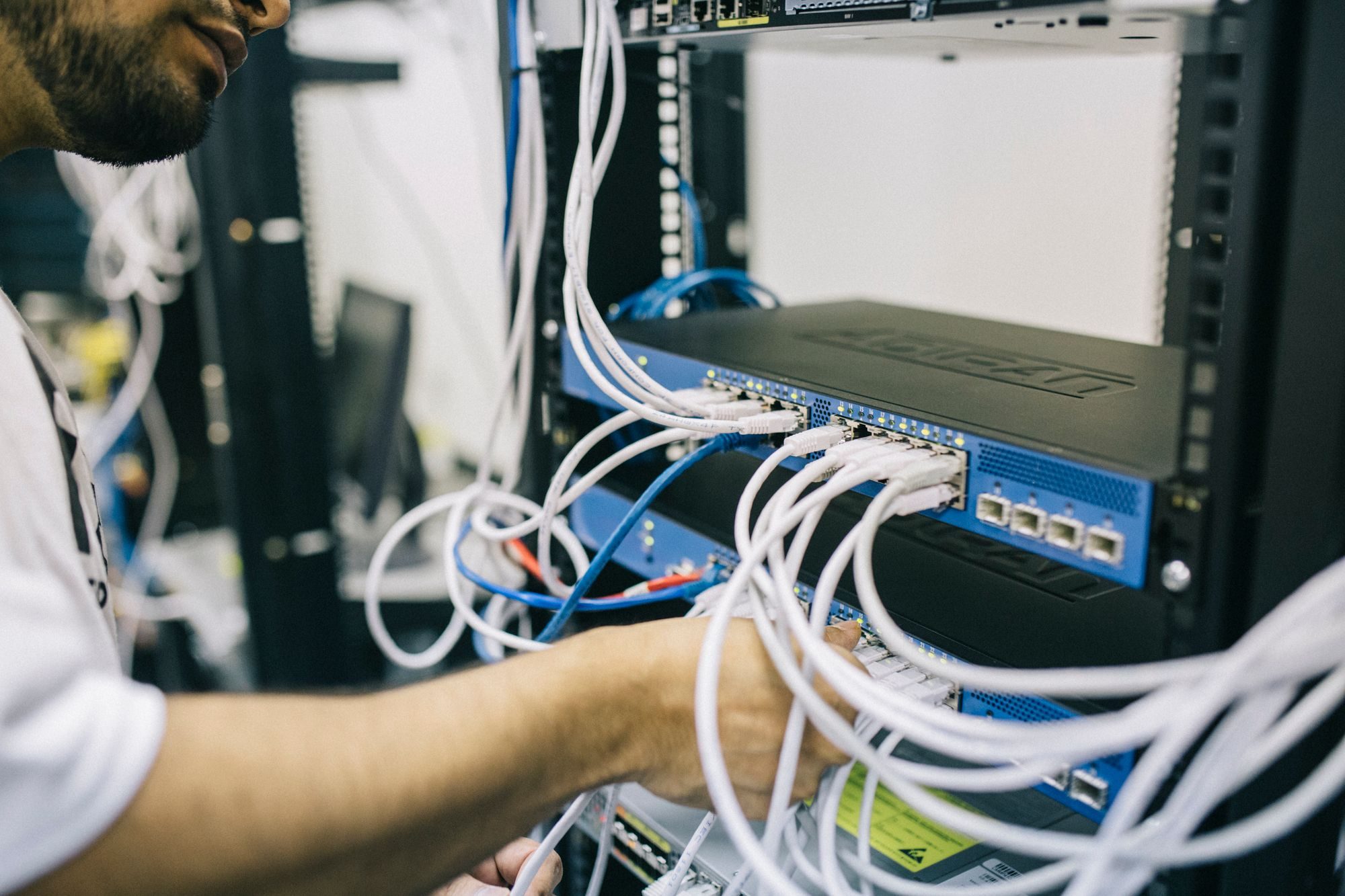 An engineer connecting network cables in a server rack
